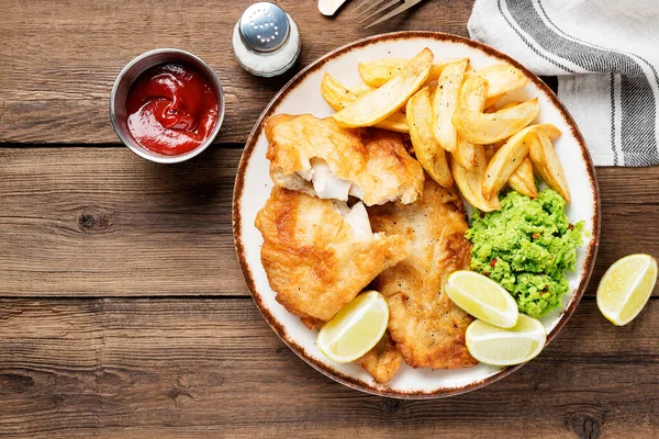 British Traditional Fish and chips with mashed peas and sauce.