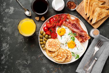 İki kızarmış yumurta, krep, domates salatası, domuz pastırması, tost, portakal suyu ve kahve ile Amerikan kahvaltısı..