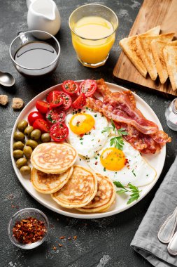 İki kızarmış yumurta, krep, domates salatası, domuz pastırması, tost, portakal suyu ve kahve ile Amerikan kahvaltısı..