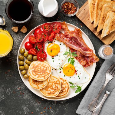 İki kızarmış yumurta, krep, domates salatası, domuz pastırması, tost, portakal suyu ve kahve ile Amerikan kahvaltısı..