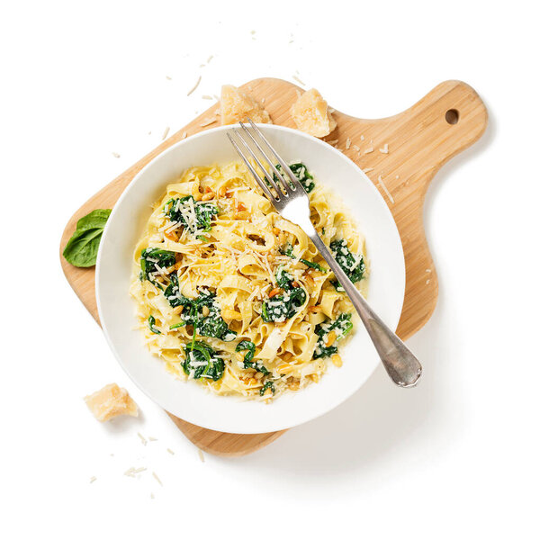 Паста феттучини со шпинатом в сливочном соусе сыра изолированы на белом фоне.