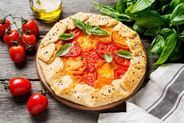 Renkli domates ve fesleğen yapraklı lezzetli ev yapımı açık turta (galette) .