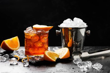Bir bardak portakallı Negroni kokteyli. Koyu taş masada rom ve vermut ile alkollü içecek..