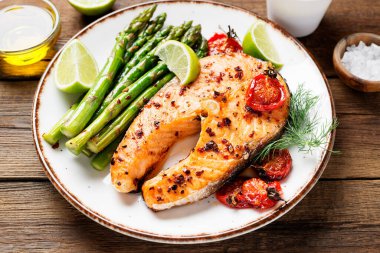 Kuşkonmaz ve domatesle süslenmiş fırında somon bifteği. .