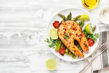 Kuşkonmaz ve domatesle süslenmiş fırında somon bifteği. .