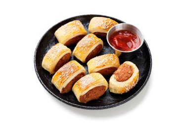 Beyaz arka planda izole edilmiş siyah tabakta nefis ev yapımı sosisli börekler.