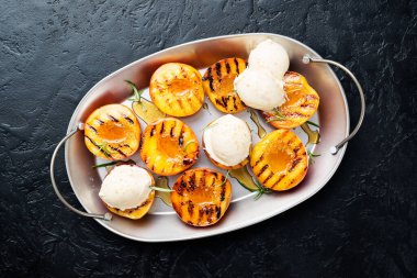 Yaz tatlısı. Olgun ızgara şeftali, ballı ve siyah arka planda dondurma..