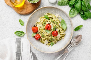 Pesto soslu makarna ve gri kasede taze fesleğen yaprağı. Açık gri arkaplan