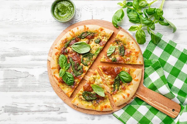 Fresh baked homemade pizza or pie with basil pesto sauce,mozzarella cheese and fresh basil leaves. top view
