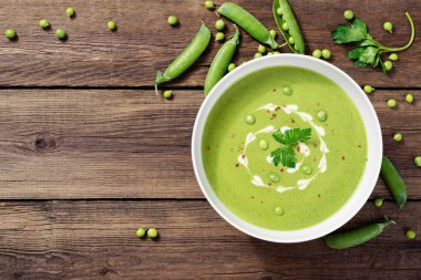 Tahta masada bir kase yeşil bezelye kremalı çorba.