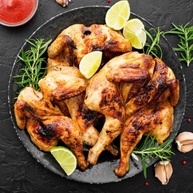 Aile yemeği için siyah arka planda serpiştirilmiş ızgara tavuk.