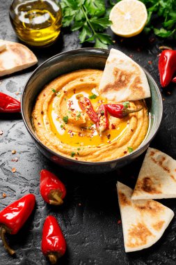 Siyah zemin üzerinde pita ekmeği olan kavrulmuş kırmızı biber humusu. en üstteki görünüm