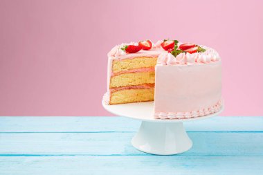 Pembe tereyağlı ve taze çilekli güzel bir pasta. Renkli arkaplan.