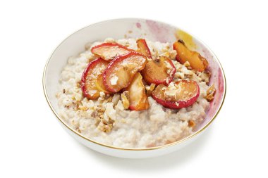 Beyaz arka planda karamelli elma ve fındıklı yulaf lapası.