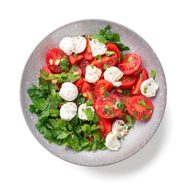 Çeri domatesli taze caprese salatası, mozzarella topları, maydanoz yaprakları ve pesto sosu. Beyaz arka planda izole edilmiş. en üstteki görünüm