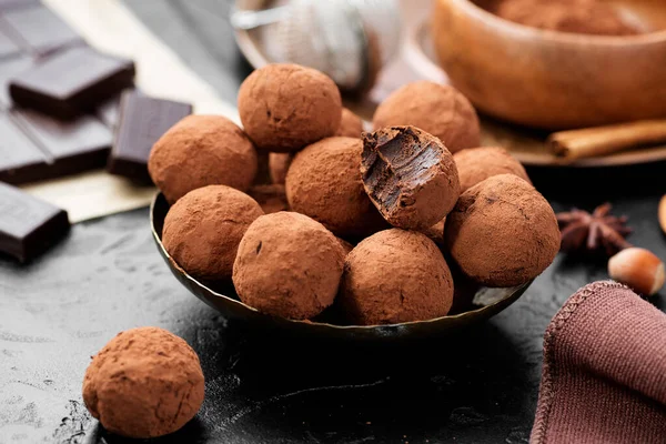 Handmade chocolate truffles covered with cocoa on black background.