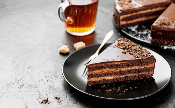 Yummy layered chocolate cake on black stone background.