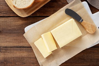 Kesme tahtasının üzerinde dilimlenmiş tereyağı parçaları, ahşap arka plan. Bir parça tereyağı. Üst görünüm