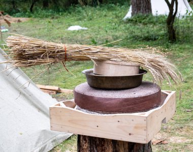 Tahıllı antik quern taş el değirmeni. Adam tahıl dolu bir değirmen taşının üst tekerleğini kaldırıyor. Eski öğütücü taşlar ellerle çevrildi..