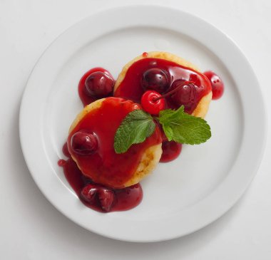 Beyaz tabakta vişne reçeli ile süzme peynir krep