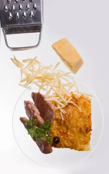 Cazuela de queso con rodajas de carne a la parrilla sobre fondo blanco en un plato transparente, cerrar — Foto de Stock
