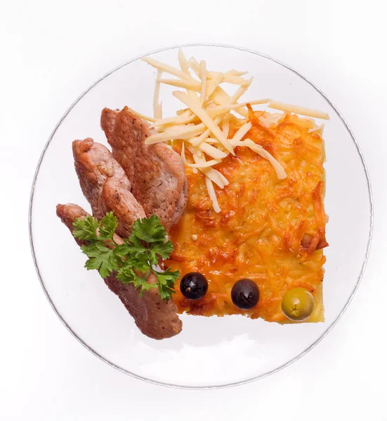 Сырная запеканка с ломтиками мяса на белом фоне на прозрачной тарелке, крупным планом — стоковое фото