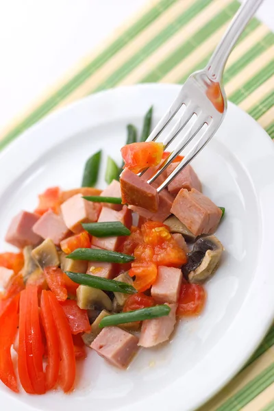Вкусный салат из ветчины, помидоров, перца и зеленого лука на белой тарелке. close up — стоковое фото