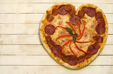 Beyaz boya ahşap arka plan üzerinde kalp pizza şekli.