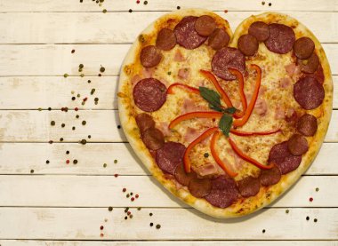 Beyaz boya ahşap arka plan üzerinde baharat ile kalp pizza şekli.