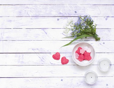 Spa mor ve mavi konsept. Çiçekler, mumlar ve kalp şekli sabun. Düz mor-beyaz ahşap arka plan, üst görünüm üzerinde yatıyordu.