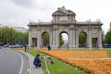 Gün batımında Puerta de Alcala'da fotoğraf çeken turistler