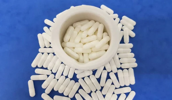 White capsules on blue background — Stock Photo, Image