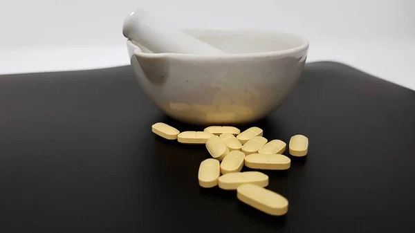 Siyah arkaplanda sarı tabletler, havan topları ve pistil — Stok fotoğraf