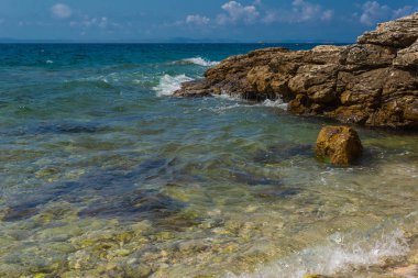 Murter, Hırvatistan, Dalmaçya'da taşlı bir plajda dalgalar kırılıyor