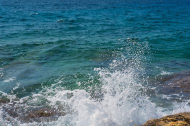 Murter, Hırvatistan, Dalmaçya'da taşlı bir plajda dalgalar kırılıyor