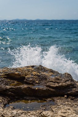 Murter, Hırvatistan, Dalmaçya'da taşlı bir plajda dalgalar kırılıyor