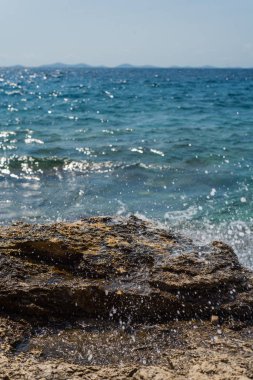 Murter, Hırvatistan, Dalmaçya'da taşlı bir plajda dalgalar kırılıyor