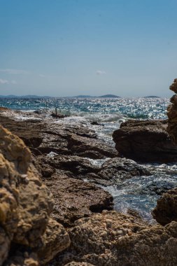 Murter, Hırvatistan, Dalmaçya'da taşlı bir plajda dalgalar kırılıyor