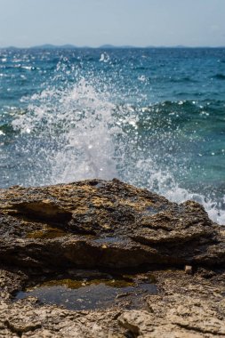 Murter, Hırvatistan, Dalmaçya'da taşlı bir plajda dalgalar kırılıyor