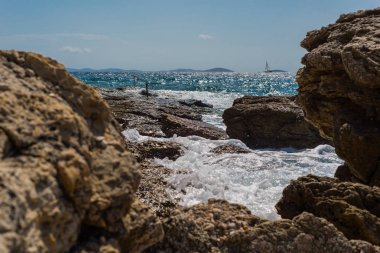 Murter, Hırvatistan, Dalmaçya'da taşlı bir plajda dalgalar kırılıyor