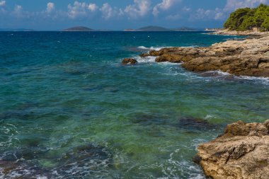 Murter, Hırvatistan, Dalmaçya'da taşlı bir plajda dalgalar kırılıyor