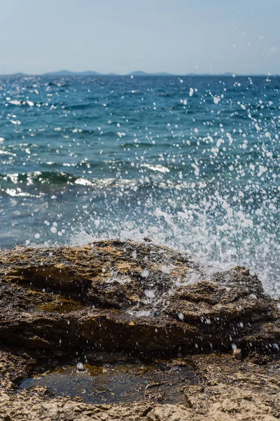 Bølger bryder på en stenet strand i Murter, Kroatien, Dalmatien - Stock-foto