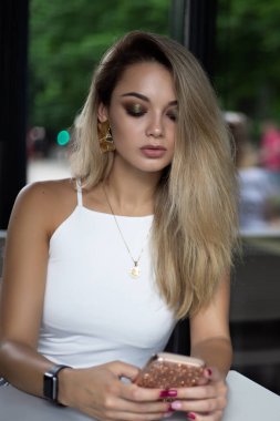 Kahve dükkanında dinlenirken cep telefonunda güzel makyaj yazıları olan çekici bir kadın. Kafkasyalı kadın boş zamanlarında kafede dinleniyor..