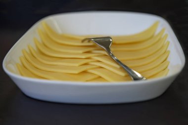 Dilimlenmiş sarı peynir beyaz tabakta kapatın. Yan görünüm