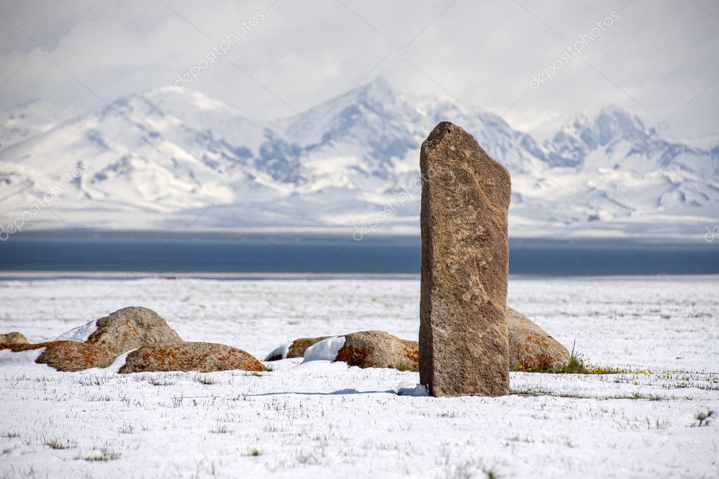 Traditional memorable stones on the shore of Son-Kul lake on the background of snow-capped mountains. Travel Kyrgyzstan