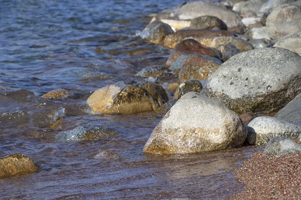 Piedras y arena en aguas cristalinas en la playa de un lago de montaña Issyl-Kul — Foto de Stock