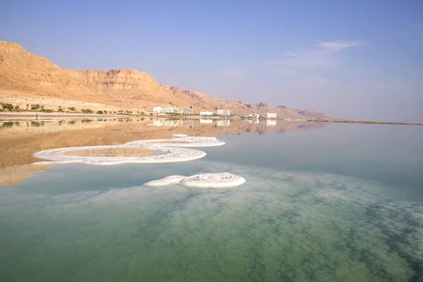 Odbicie gór, hoteli i palm w wodzie Morza Martwego z formacjami solnymi — Zdjęcie stockowe