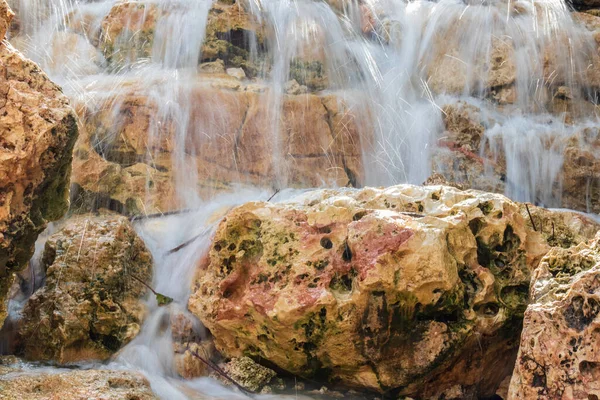 Медленное движение струй воды искусственных водопадов на живописных текстурированных камнях — стоковое фото