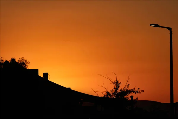 Silhuetas de casas e árvores no fundo do colorido céu do pôr do sol — Fotografia de Stock