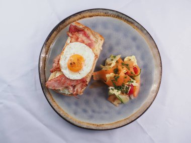 Kızarmış yumurta, pastırma, peynir ve sebzeli sandviç.